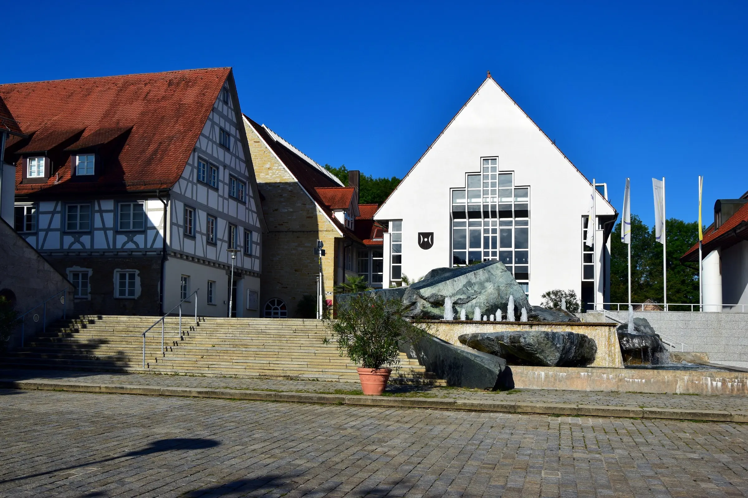 Rathaus von Schwieberdingen am Schloßhof mit Brunnen und Fachwerkhaus an einem Sommermorgen